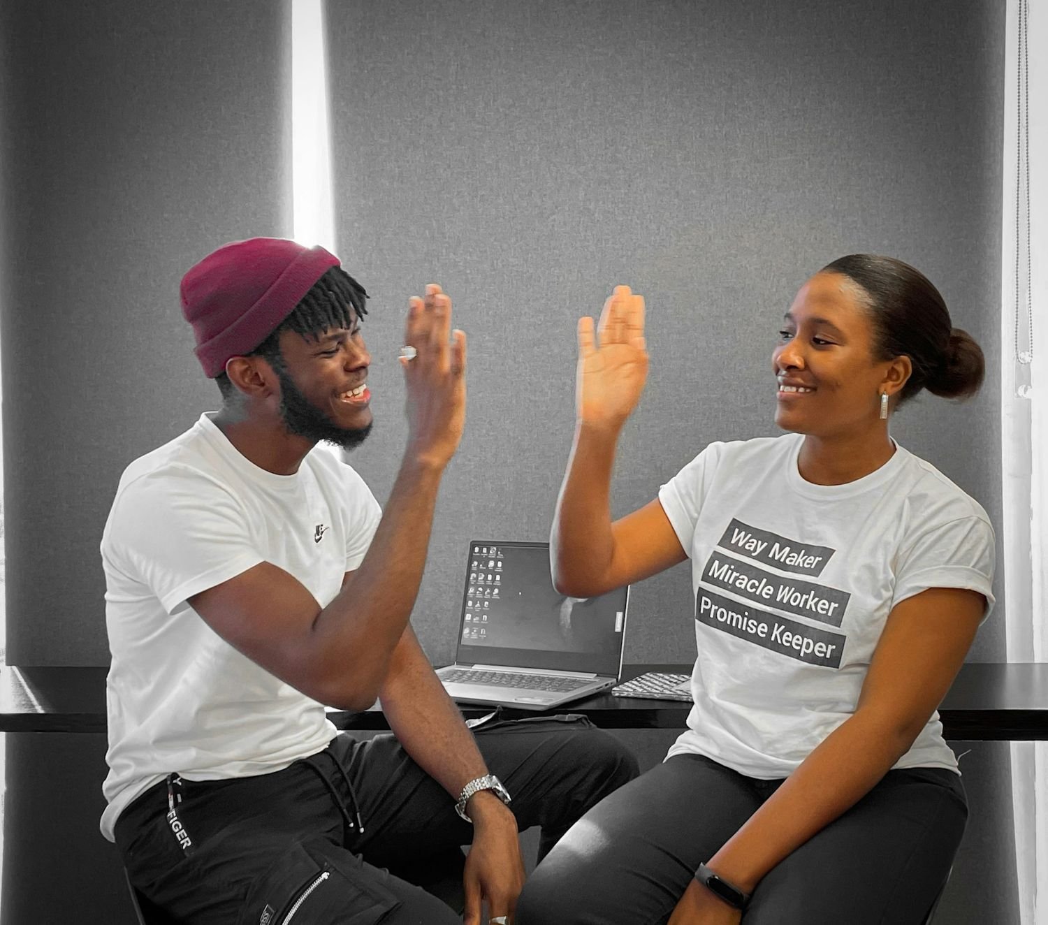 Two creatives celebrating with a high five at their desks