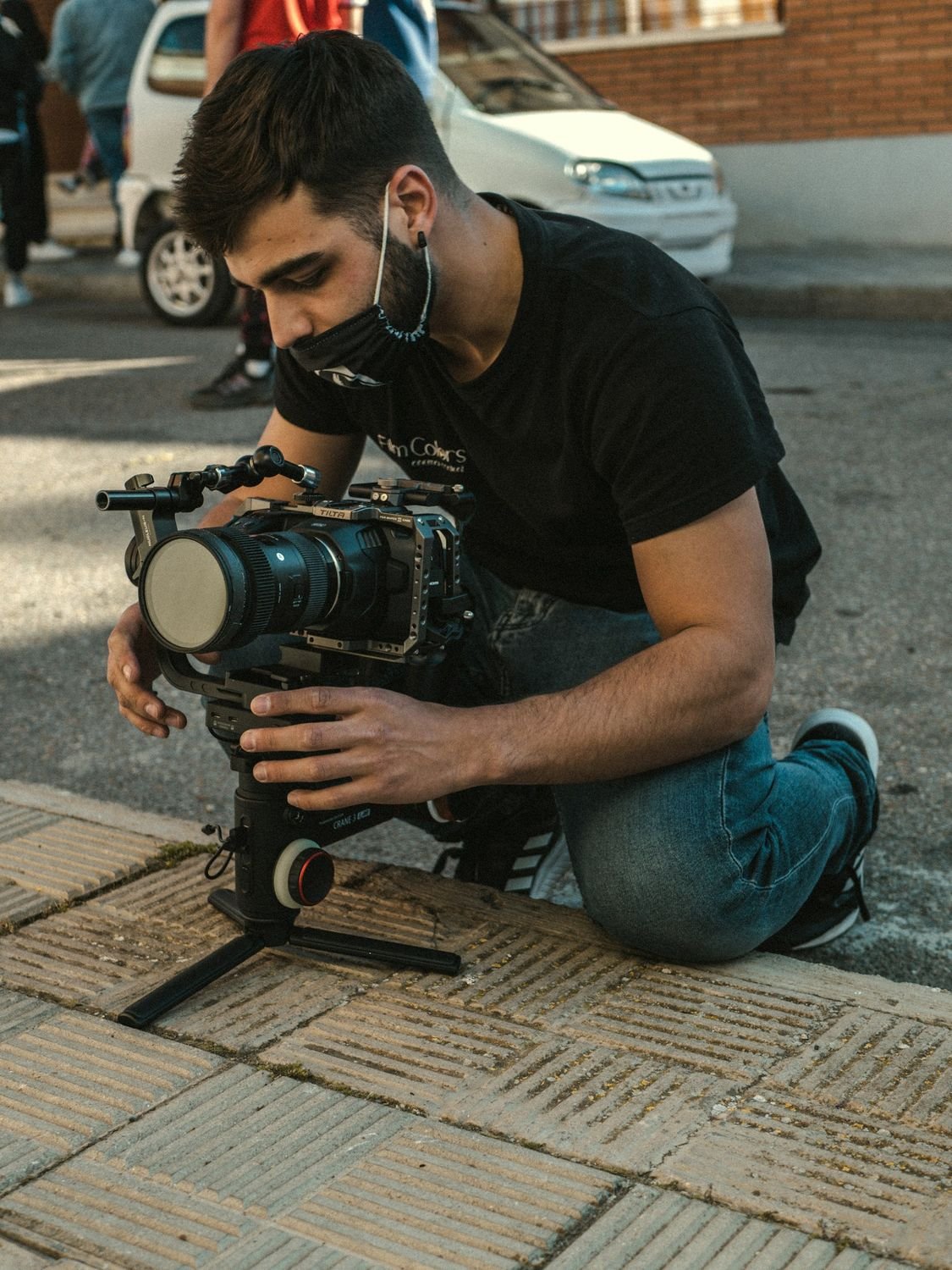 Camera operator kneeling with a cinema camera rig