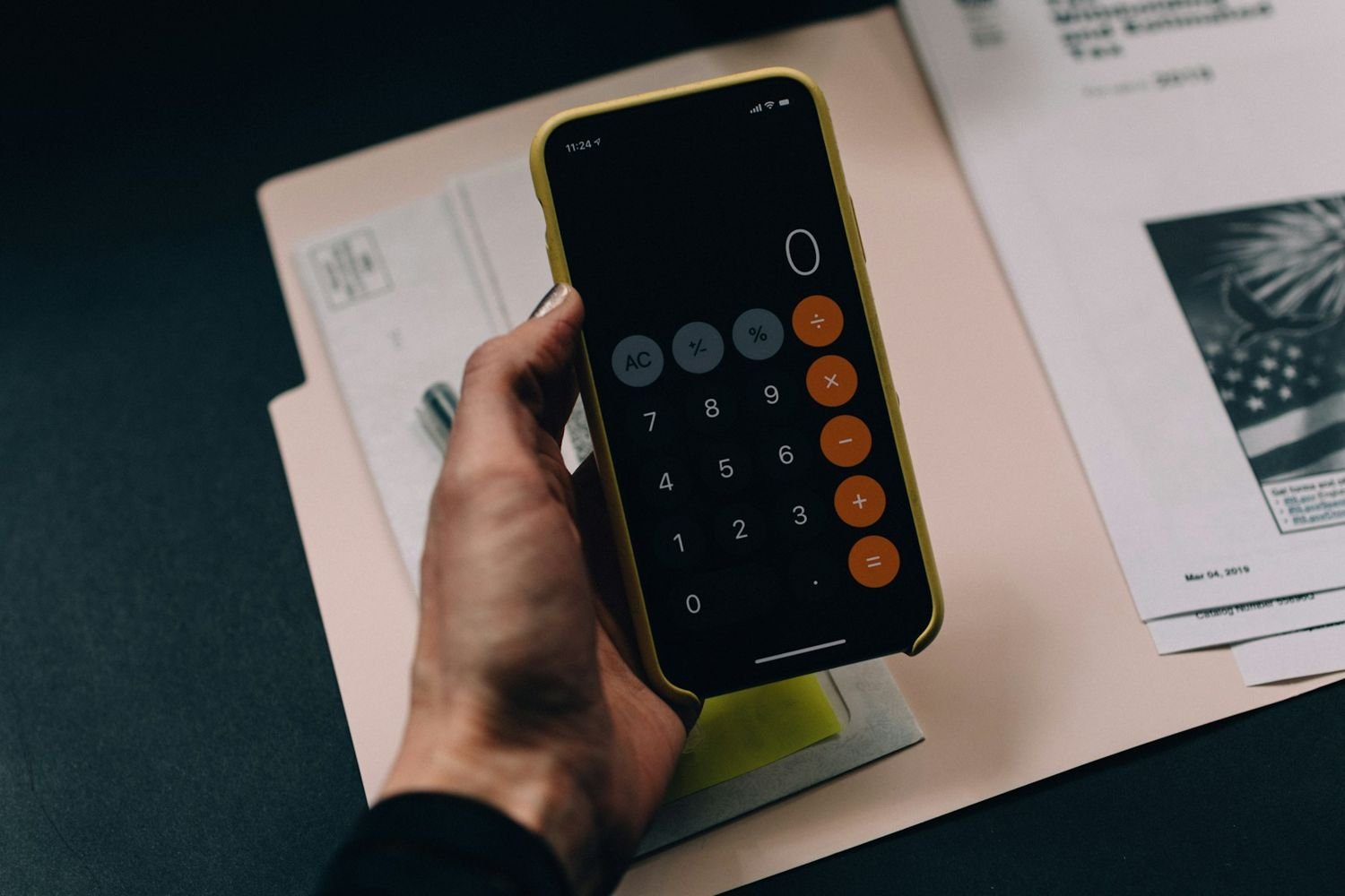 Hand holding a calculator over financial paperwork