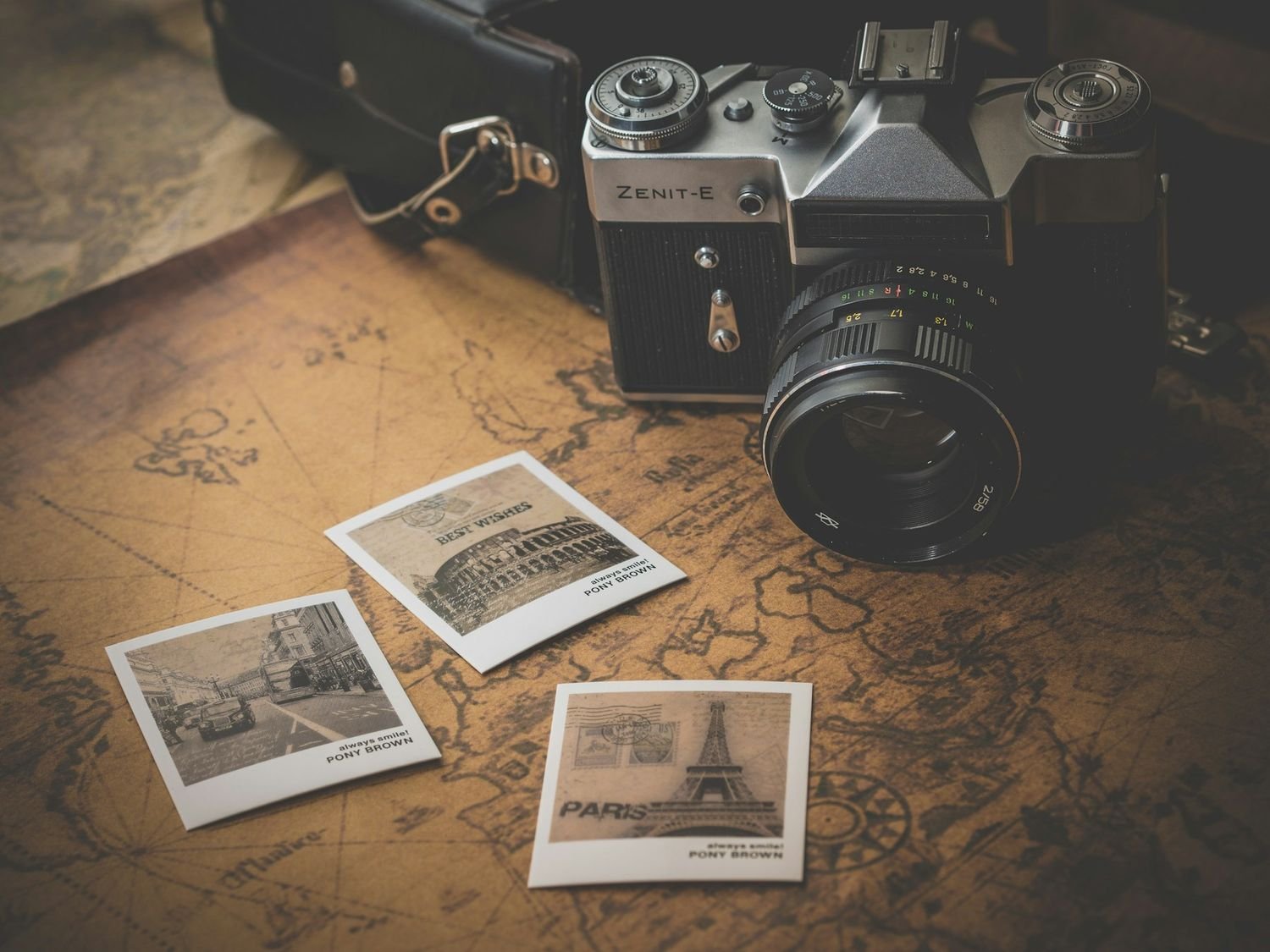 Vintage camera resting on old photographs and a map