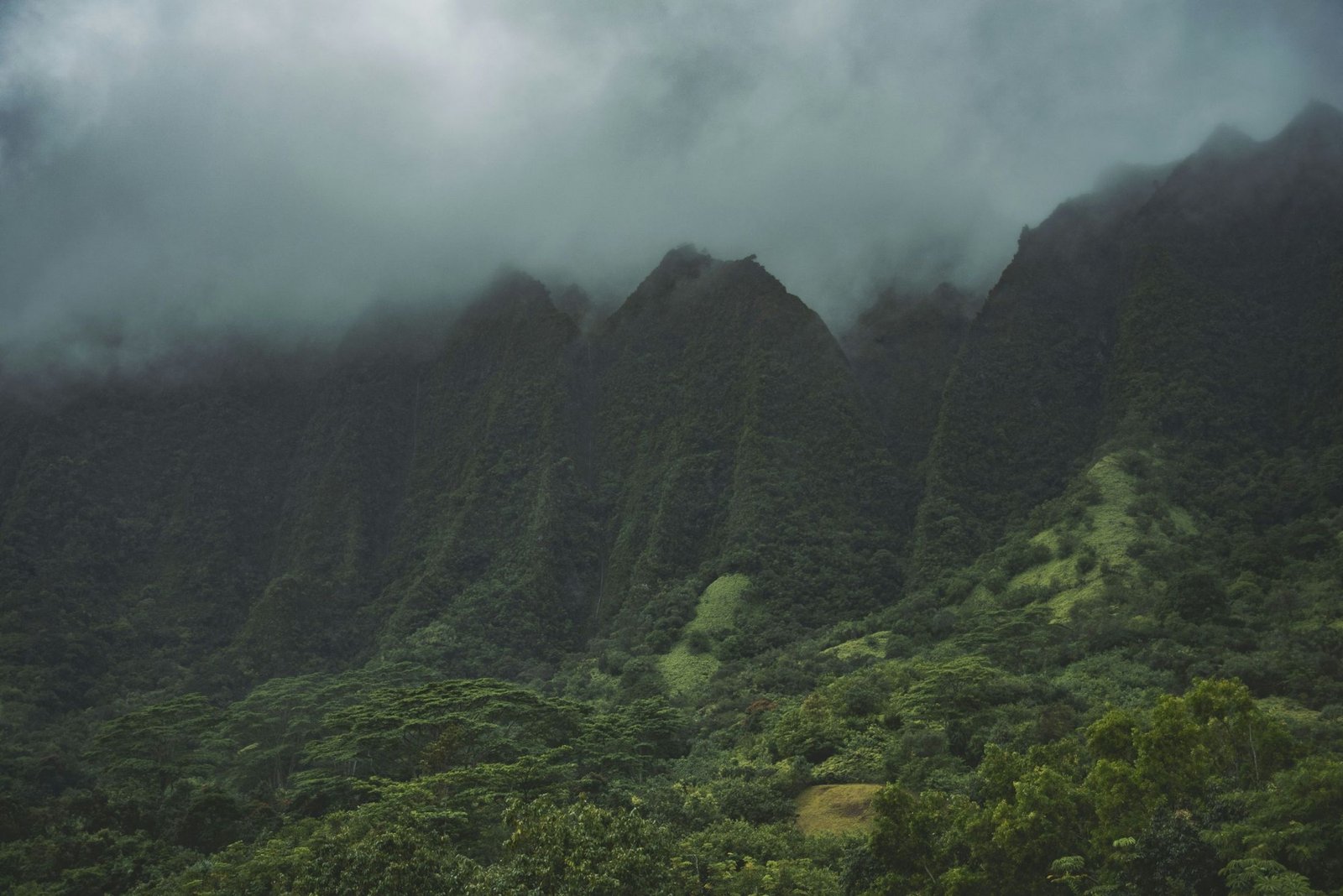 Clouds rolling over steep green mountain ridges