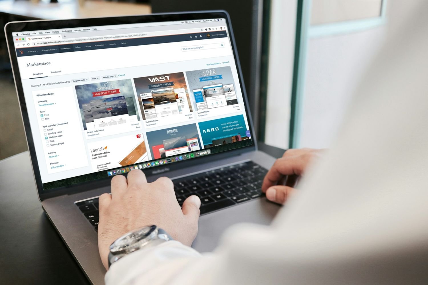 Hands typing on a laptop showing a website